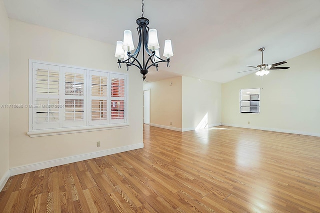 spare room with ceiling fan with notable chandelier, light wood-type flooring, and lofted ceiling