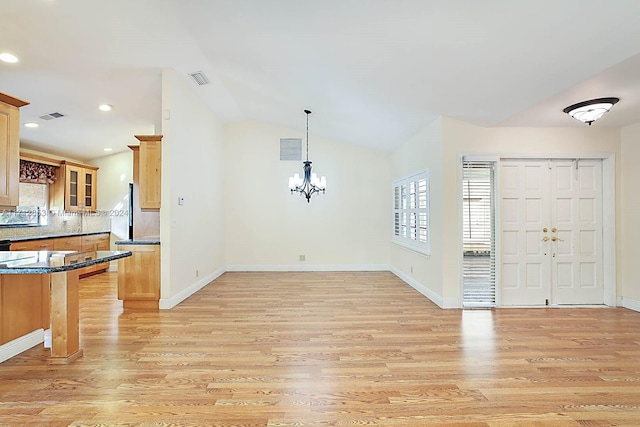 entryway featuring a chandelier, lofted ceiling, and light hardwood / wood-style floors