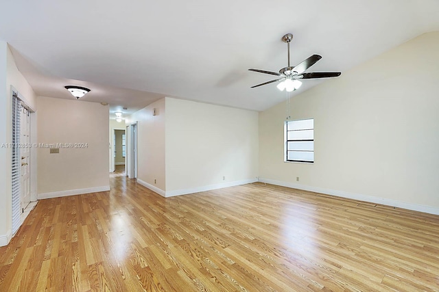 spare room with light wood-type flooring, vaulted ceiling, and ceiling fan