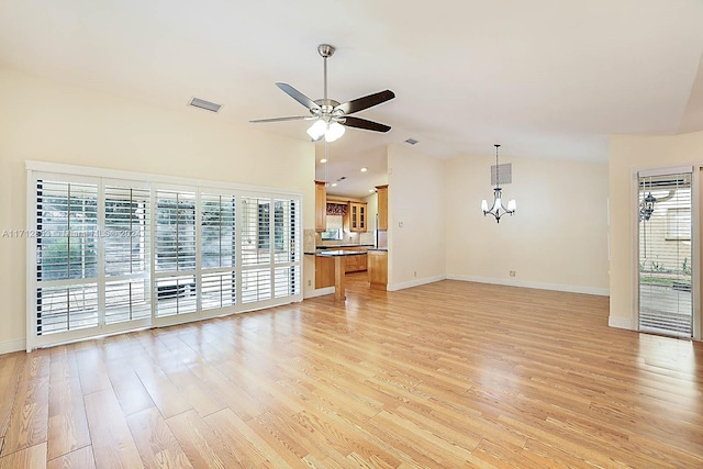 unfurnished living room with ceiling fan with notable chandelier, light hardwood / wood-style floors, and a wealth of natural light