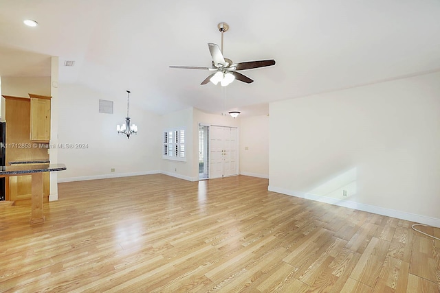 unfurnished living room with light wood-type flooring, ceiling fan with notable chandelier, and lofted ceiling