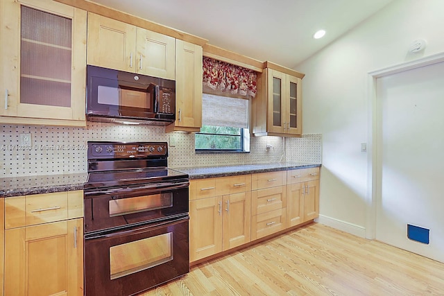 kitchen with dark stone counters, light hardwood / wood-style flooring, black appliances, and light brown cabinets