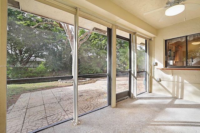 doorway to outside featuring a textured ceiling, carpet floors, and ceiling fan