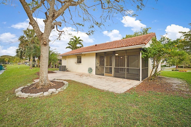 rear view of house featuring a sunroom, a patio area, a lawn, and central AC