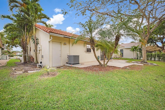 rear view of property with cooling unit, a patio area, and a lawn