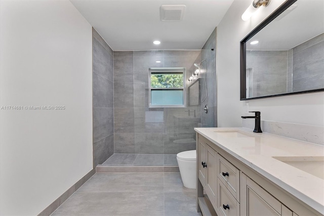 bathroom with tiled shower, vanity, and toilet