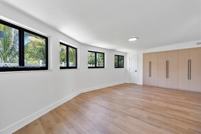 unfurnished bedroom featuring multiple windows and light hardwood / wood-style floors