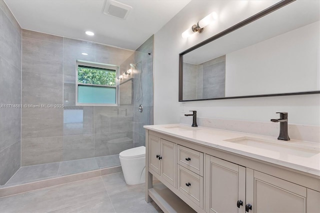 bathroom with vanity, toilet, tile patterned flooring, and a tile shower