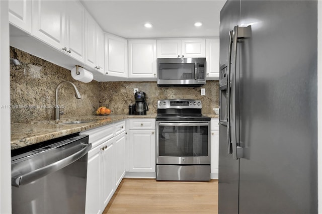 kitchen with sink, white cabinets, light stone counters, decorative backsplash, and appliances with stainless steel finishes