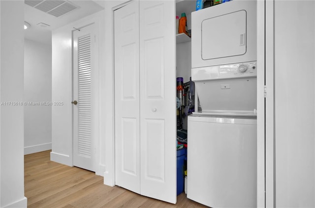 laundry area featuring light hardwood / wood-style flooring and stacked washer and dryer