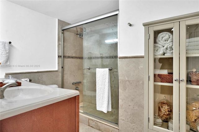 bathroom with tile walls, a shower with door, and vanity