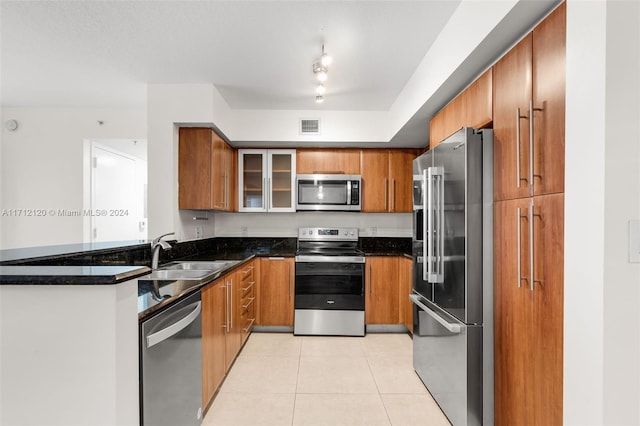 kitchen featuring dark stone countertops, light tile patterned floors, sink, and appliances with stainless steel finishes