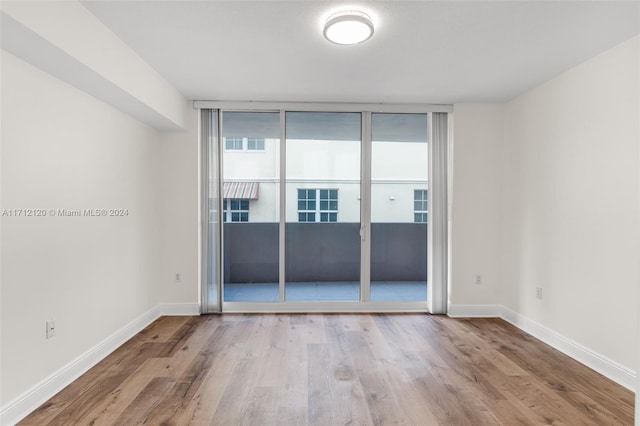 spare room with light hardwood / wood-style floors and a wall of windows