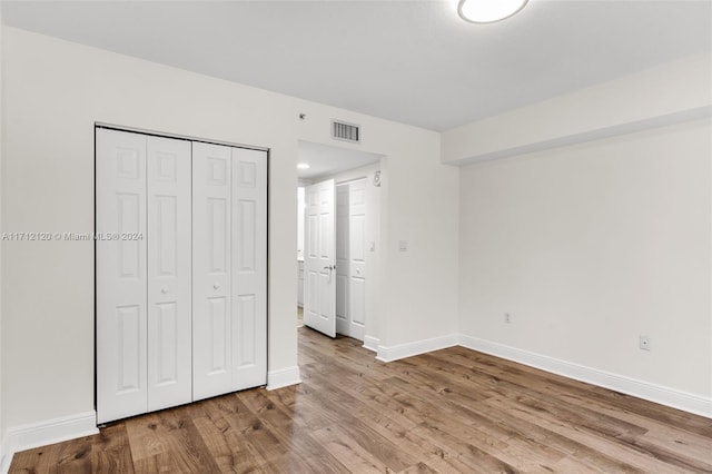 unfurnished bedroom with light hardwood / wood-style flooring and a closet