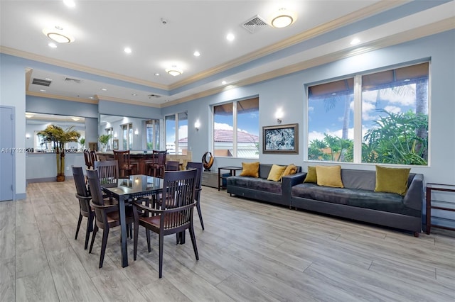 dining room featuring a raised ceiling, light hardwood / wood-style flooring, and ornamental molding