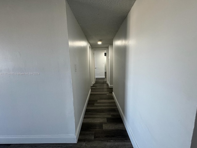 hallway with dark hardwood / wood-style flooring and a textured ceiling