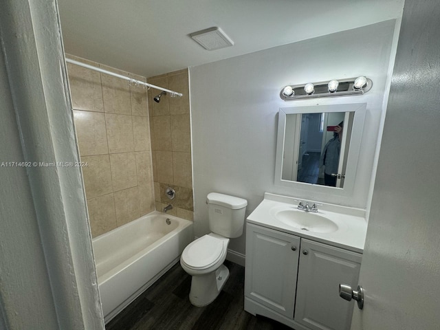 full bathroom with vanity, hardwood / wood-style floors, tiled shower / bath combo, and toilet