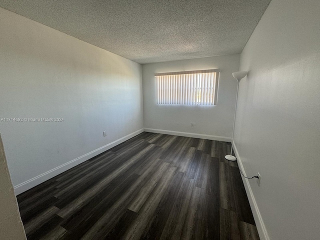 spare room with dark hardwood / wood-style flooring and a textured ceiling