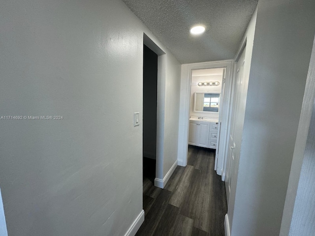 corridor featuring dark hardwood / wood-style flooring and a textured ceiling