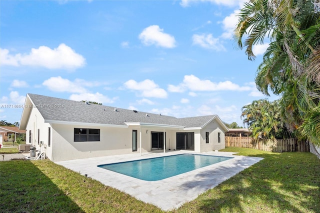 rear view of property featuring a fenced in pool, a patio area, and a lawn