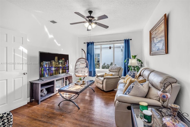 living room with ceiling fan, dark hardwood / wood-style floors, and a textured ceiling