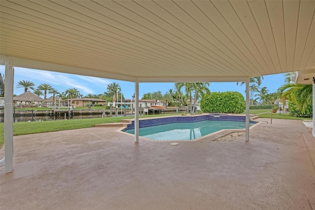 view of swimming pool featuring a patio, a water view, and a lawn