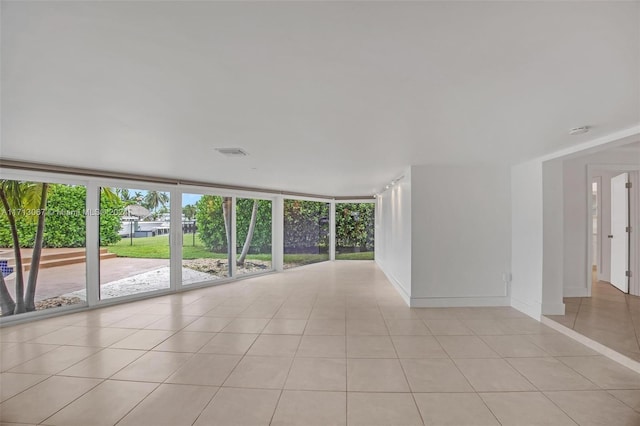 tiled empty room featuring a wall of windows