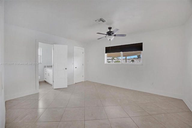 unfurnished bedroom featuring ensuite bath, ceiling fan, and light tile patterned floors