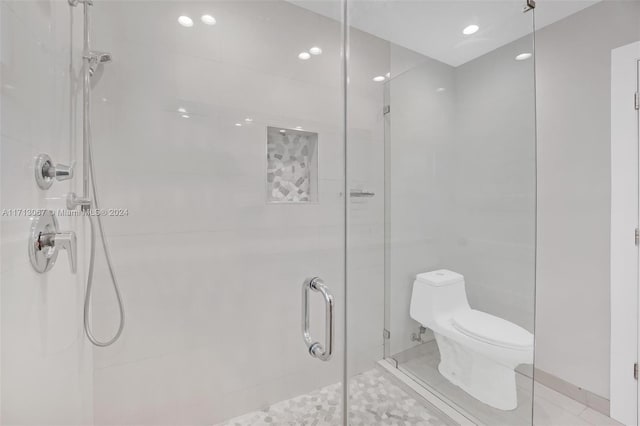 bathroom with tile patterned flooring, toilet, and a shower with shower door