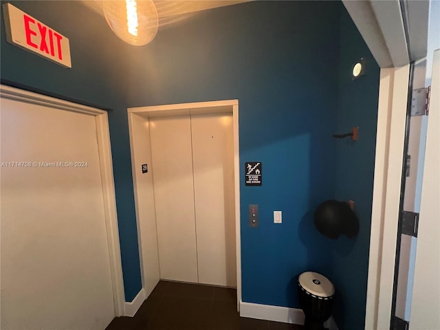 hall featuring dark tile patterned flooring and elevator