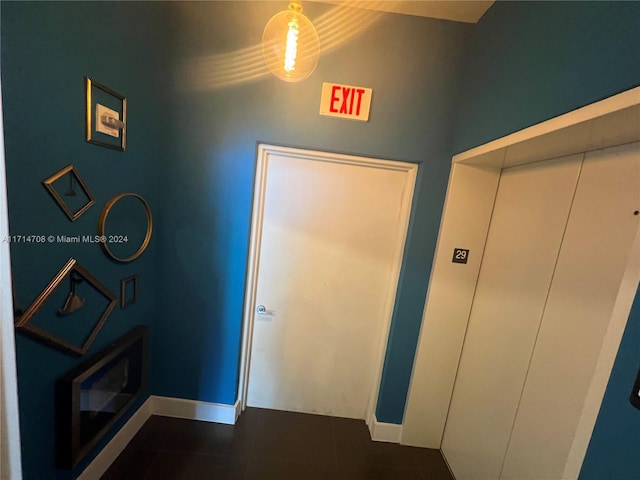 corridor featuring elevator and dark tile patterned flooring