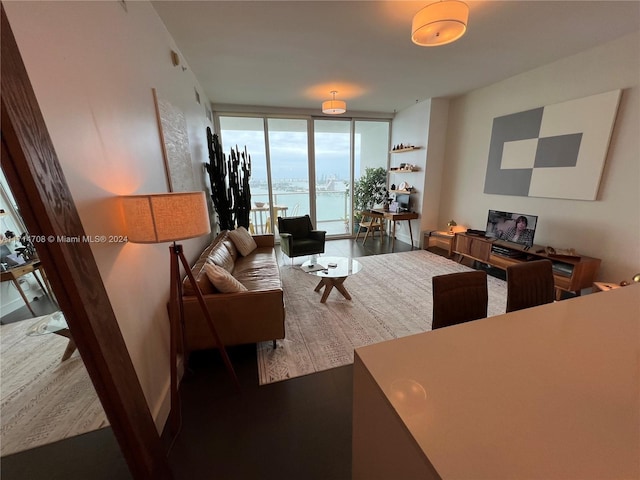 living room featuring dark hardwood / wood-style floors, floor to ceiling windows, and a water view