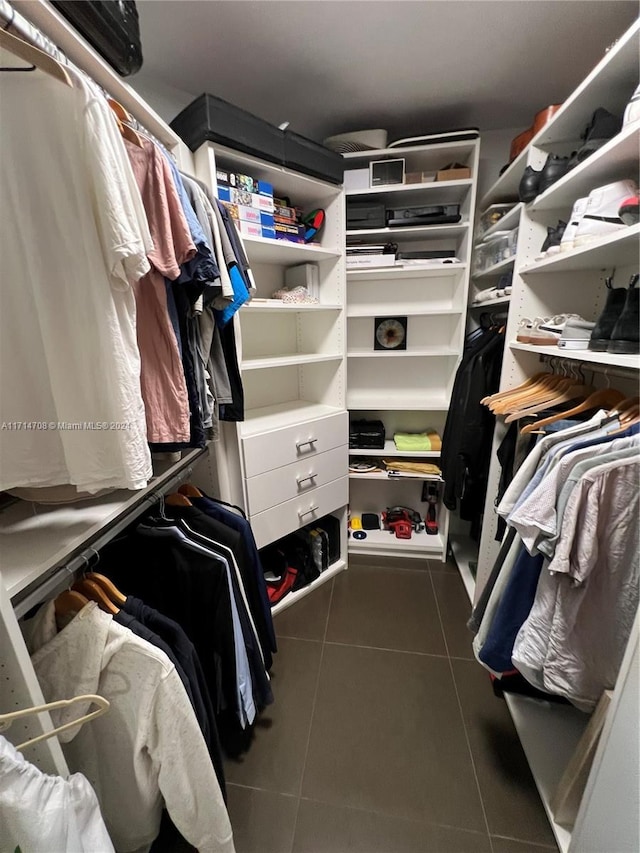 walk in closet featuring dark tile patterned flooring