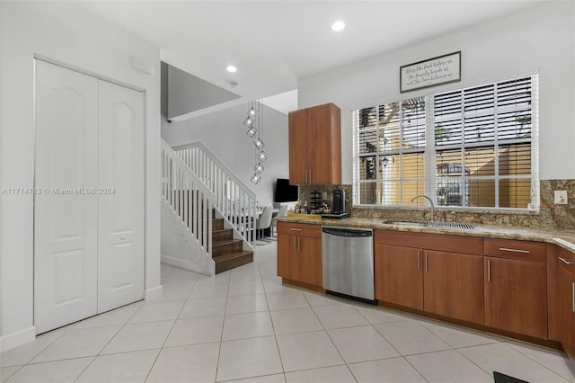 kitchen featuring sink, stainless steel dishwasher, decorative backsplash, light tile patterned floors, and light stone counters