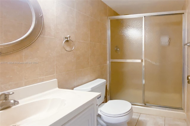 bathroom with vanity, tile patterned flooring, toilet, tile walls, and an enclosed shower