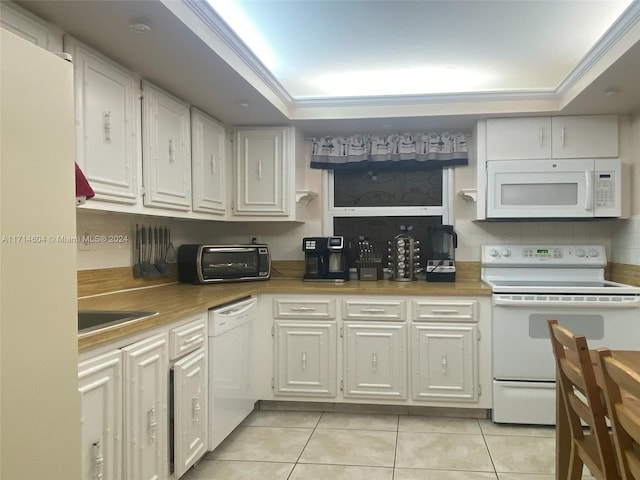 kitchen featuring a raised ceiling, light tile patterned floors, white cabinets, and white appliances