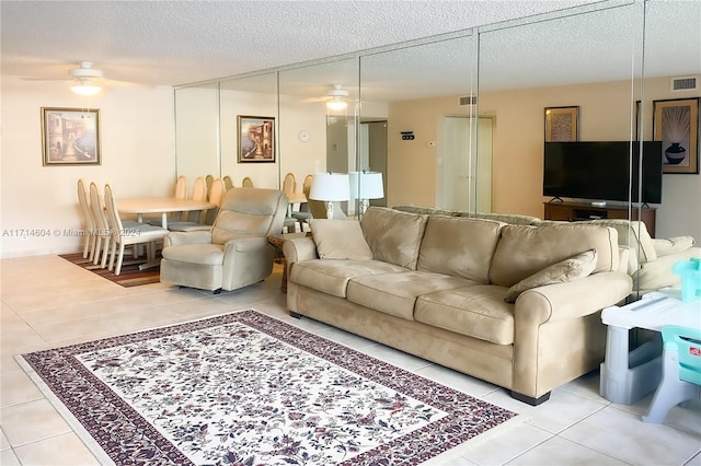 living room featuring ceiling fan, light tile patterned flooring, and a textured ceiling