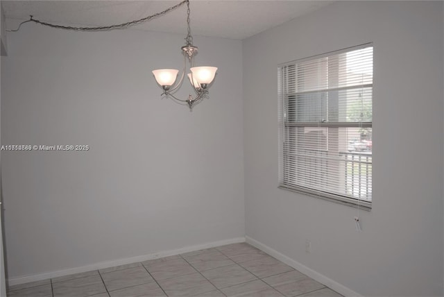 tiled empty room with a notable chandelier