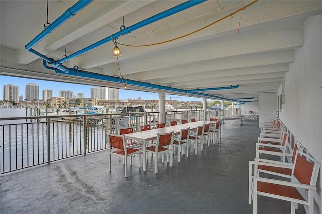 unfurnished dining area featuring beam ceiling, a water view, and concrete flooring