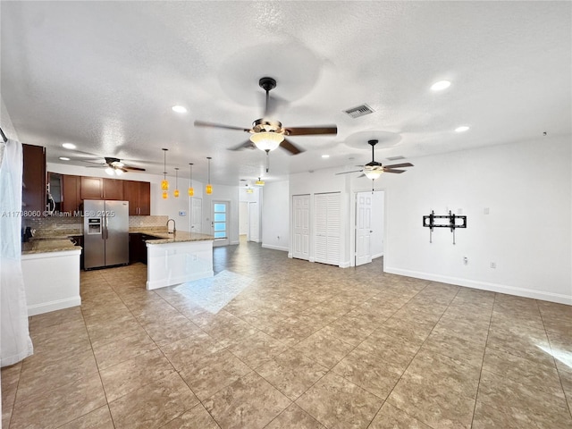 kitchen featuring hanging light fixtures, stainless steel refrigerator with ice dispenser, tasteful backsplash, a textured ceiling, and a kitchen island