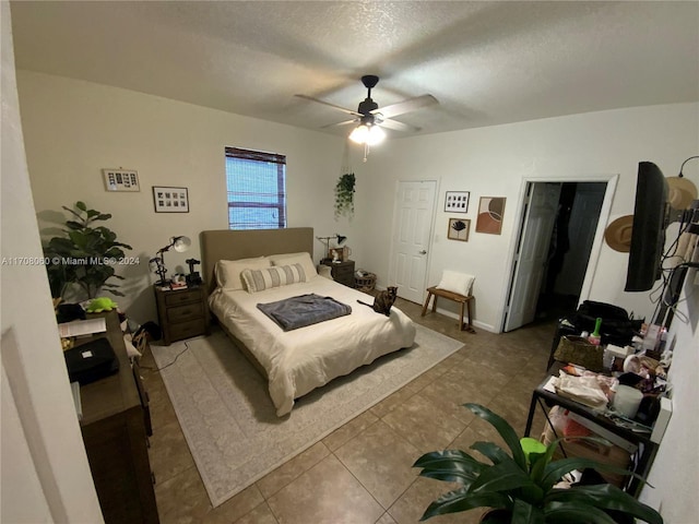 bedroom featuring ceiling fan, light tile patterned flooring, a textured ceiling, and a closet