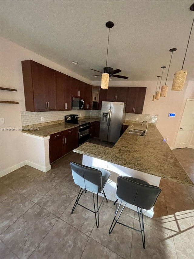 kitchen with sink, kitchen peninsula, a breakfast bar area, and appliances with stainless steel finishes