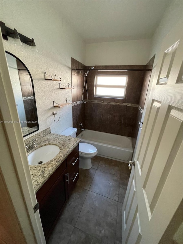 full bathroom featuring tile patterned floors, vanity, tiled shower / bath, and toilet