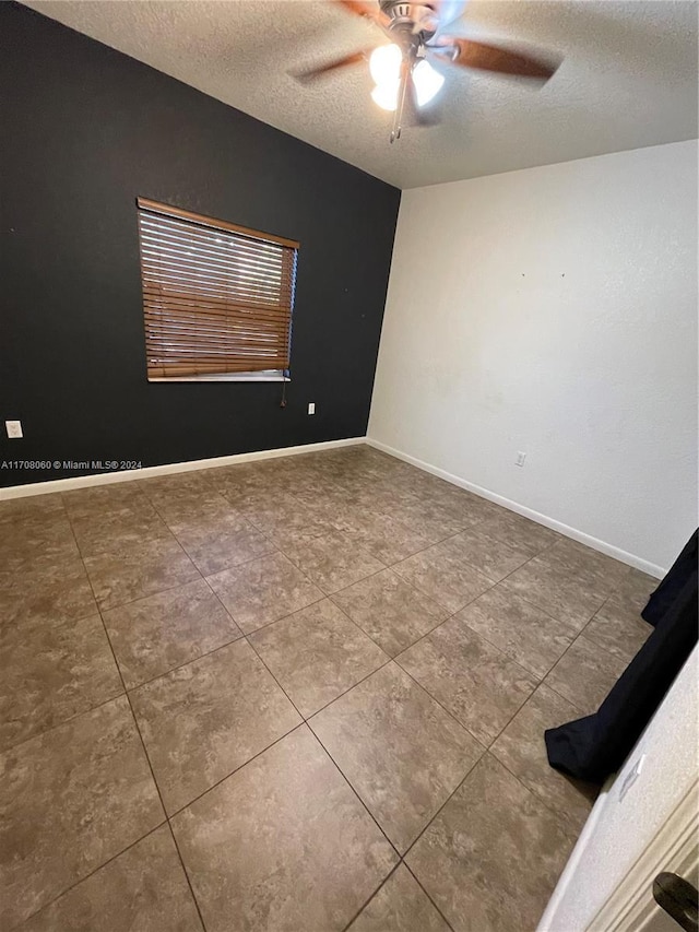 tiled empty room with ceiling fan and a textured ceiling