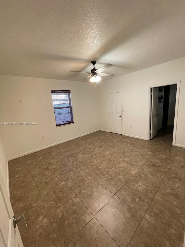 unfurnished room with ceiling fan and a textured ceiling