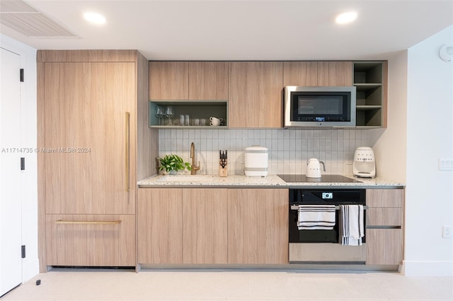 kitchen featuring decorative backsplash, light brown cabinetry, light stone counters, and black appliances