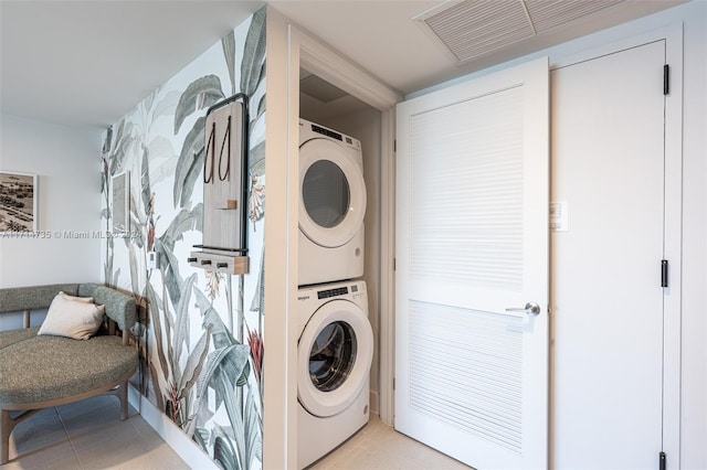 laundry area with light tile patterned floors and stacked washer / drying machine