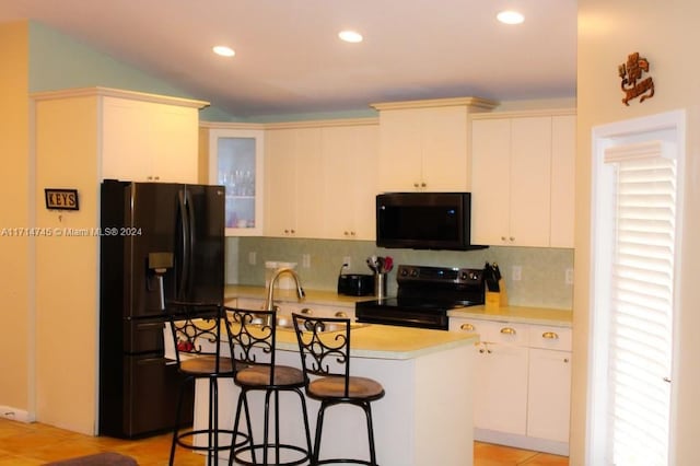 kitchen featuring a kitchen bar, backsplash, black appliances, white cabinets, and a kitchen island