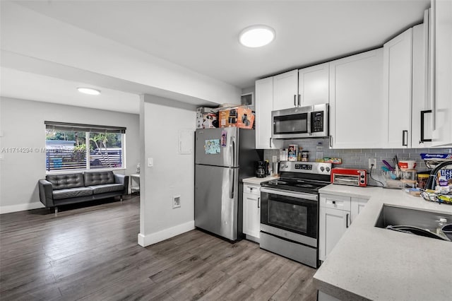 kitchen with white cabinets, backsplash, stainless steel appliances, and hardwood / wood-style flooring