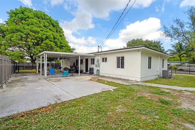 back of house featuring a carport, a yard, cooling unit, and a patio area